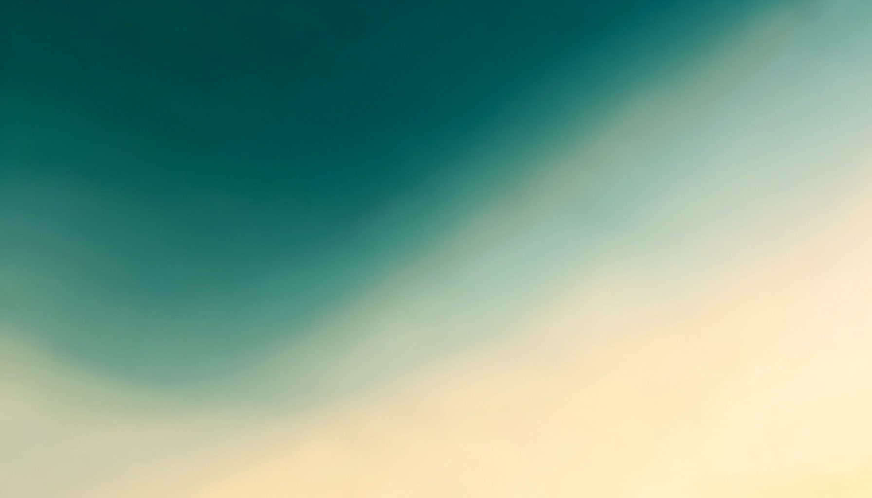Soft gradient of deep teal blending into warm cream and pale gold tones, suggesting evening light on a calm campus sky